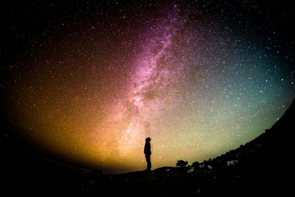 man standing galaxy northern lights colorful