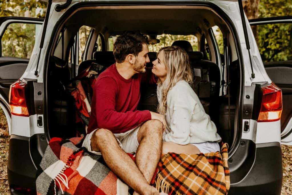couple with blankets sitting in back of vehicle love