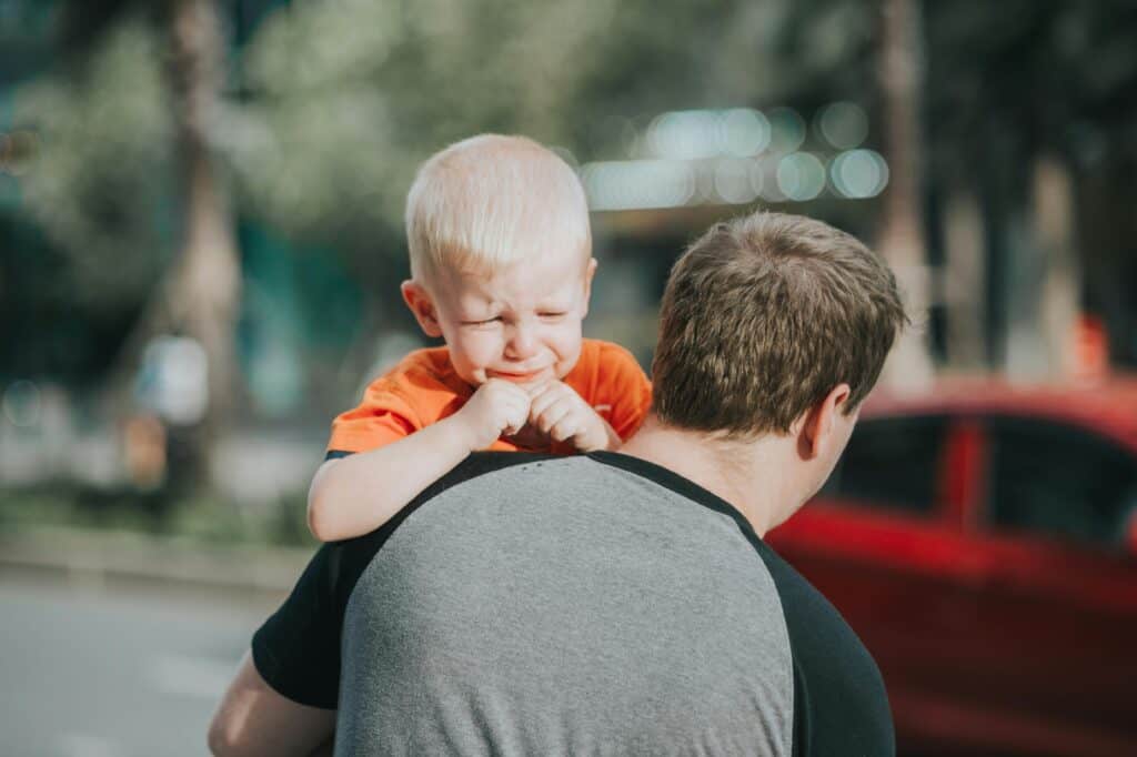 man holding crying toddler son