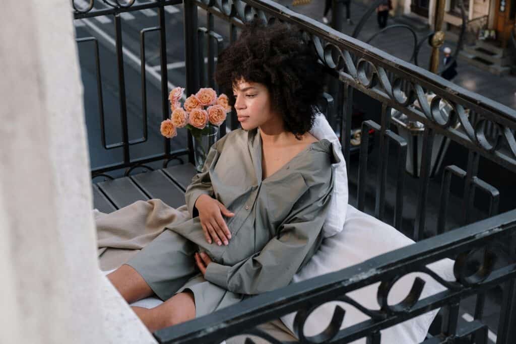 pregnant woman sitting on balcony thinking