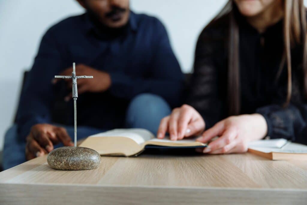 couple reading Bible metal cross sculpture