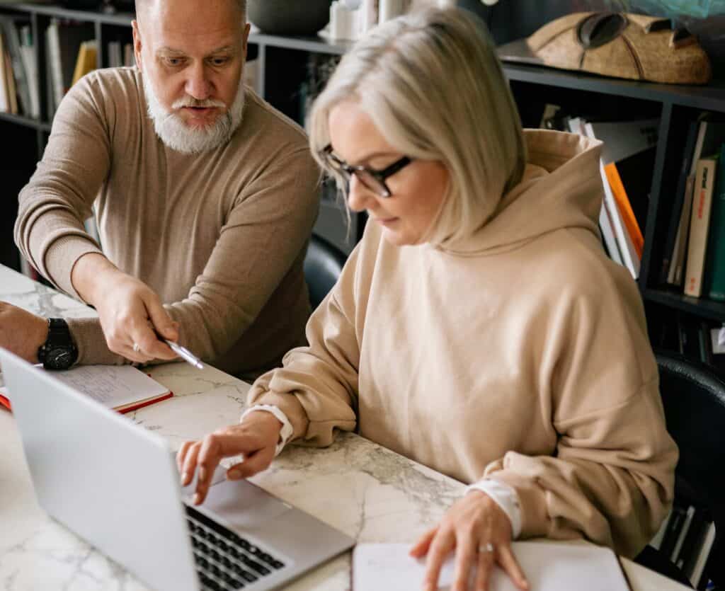 older couple looking at computer together writing things down