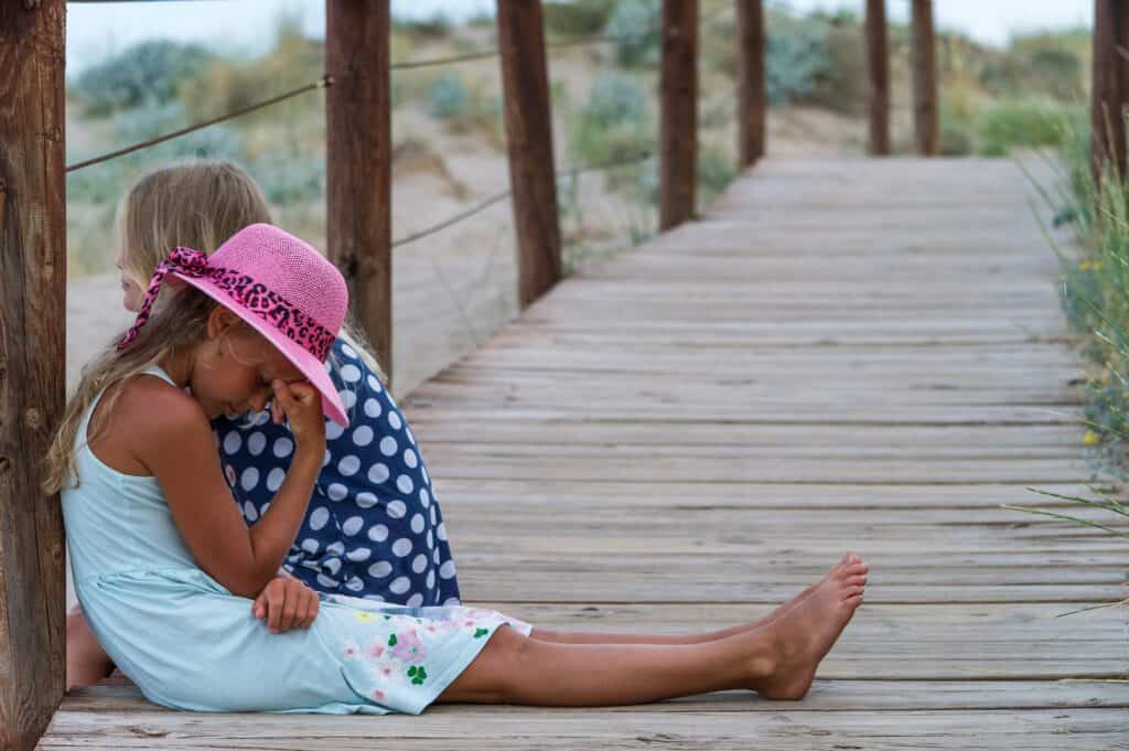 girl on pier with friend looking sad