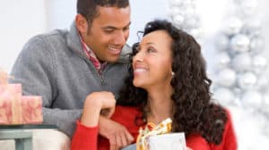 Husband And Wife Affectionately Exchanging Christmas Gifts