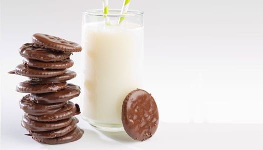 Homemade Thin Mints stacked next to a tall glass of milk