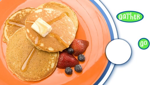 Shown from above, an orange plate with three pancakes with a bit of fruit on the side