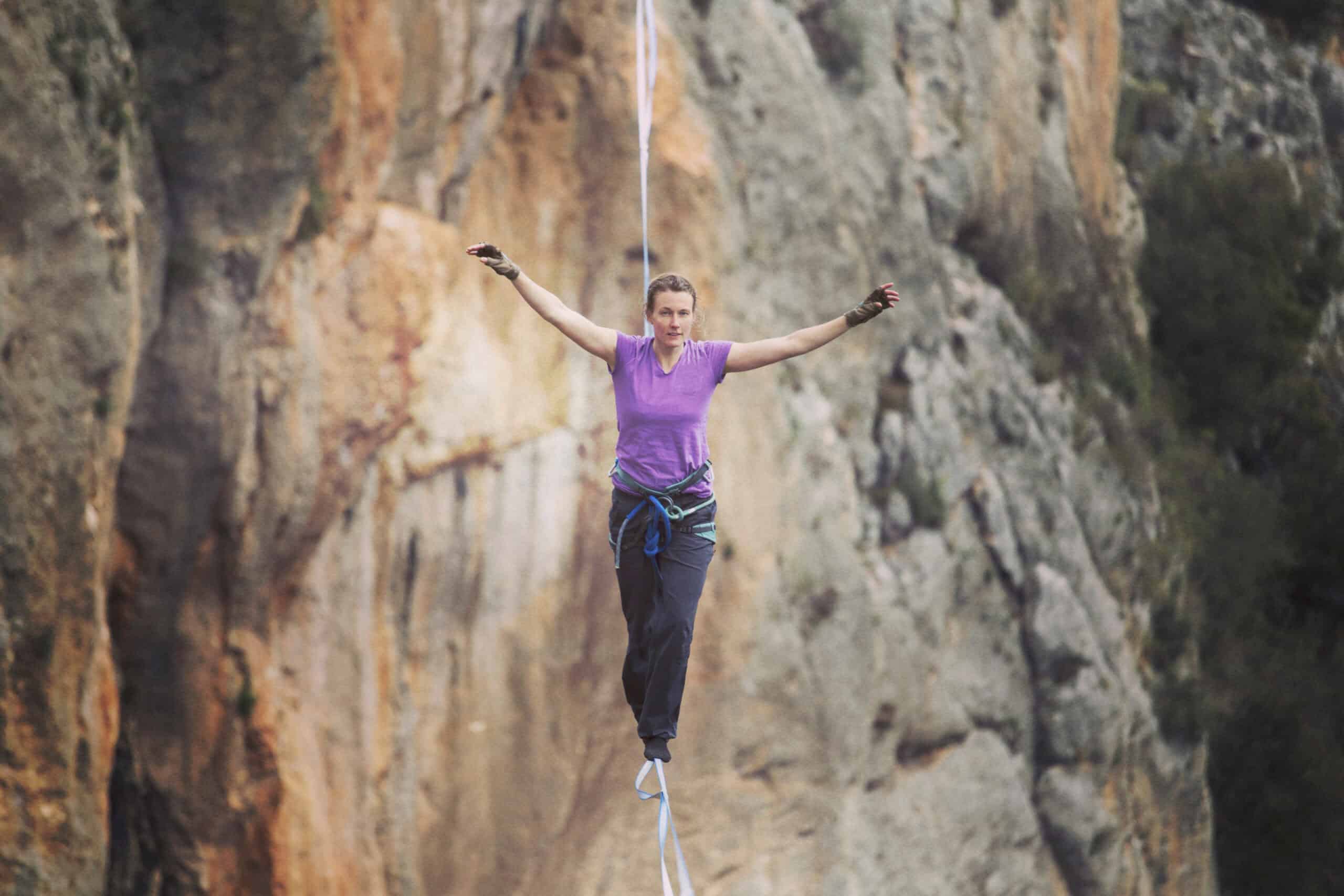 A woman is walking along a tightrope in nature.